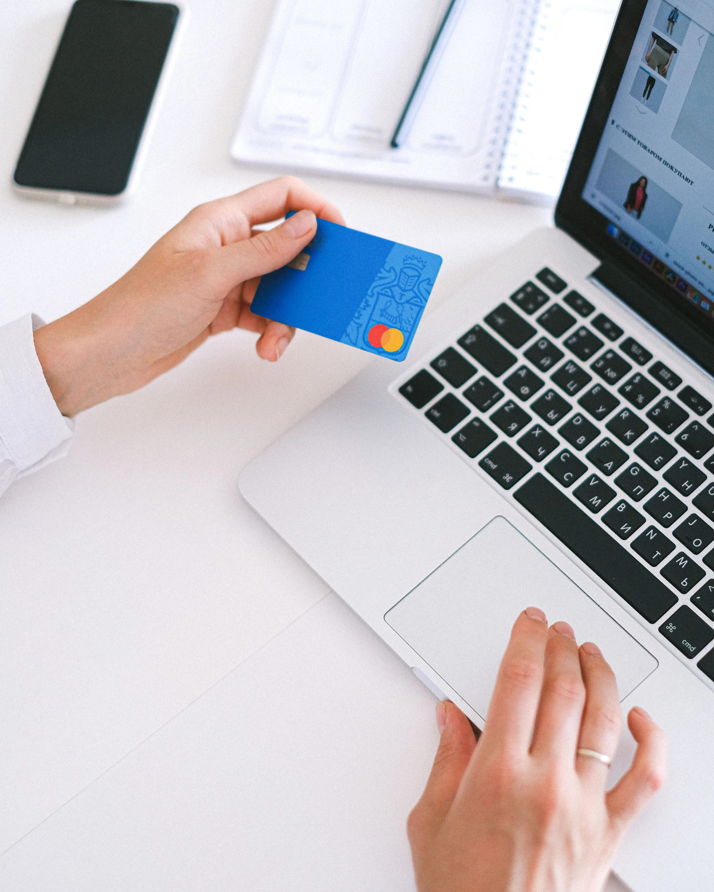 Une main tient sa carte bancaire devant l’ordinateur portable, au moment de préparer un virement